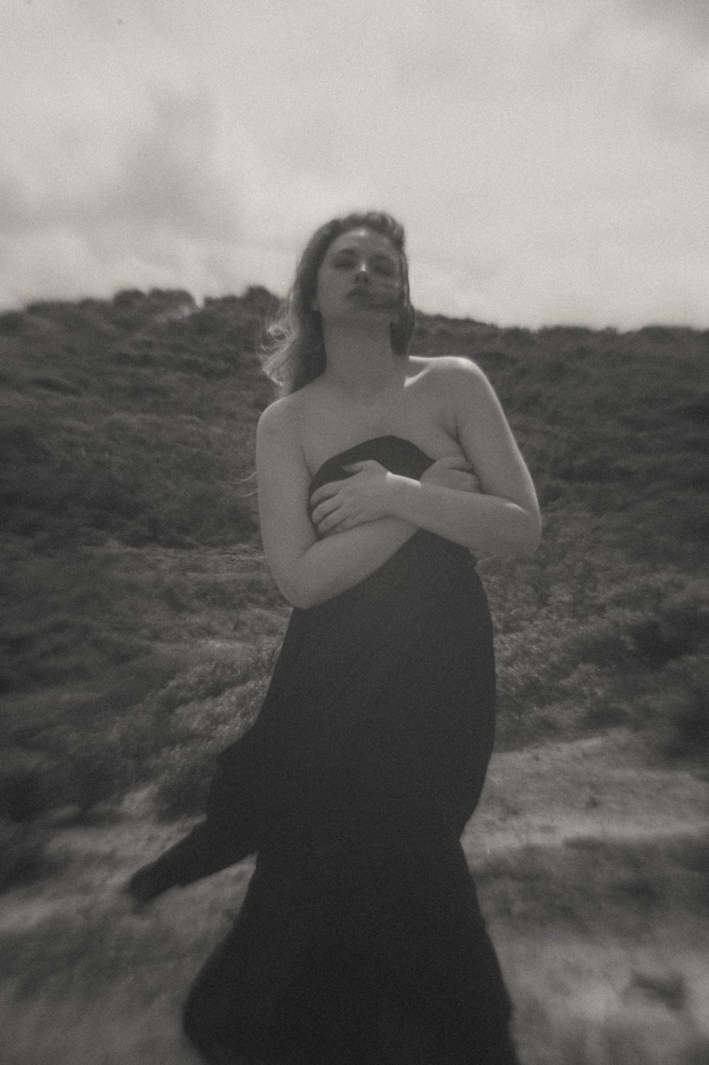 Moody black and white portraits captured against a natural hillside landscape.