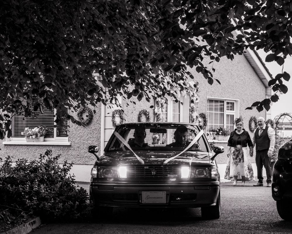 Classic black cars lined up at night with headlights glowing.