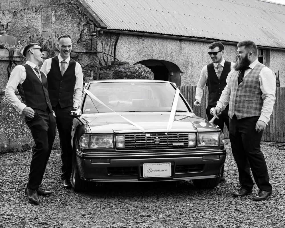 Vintage cars parked outside a wedding venue with guests gathering around.