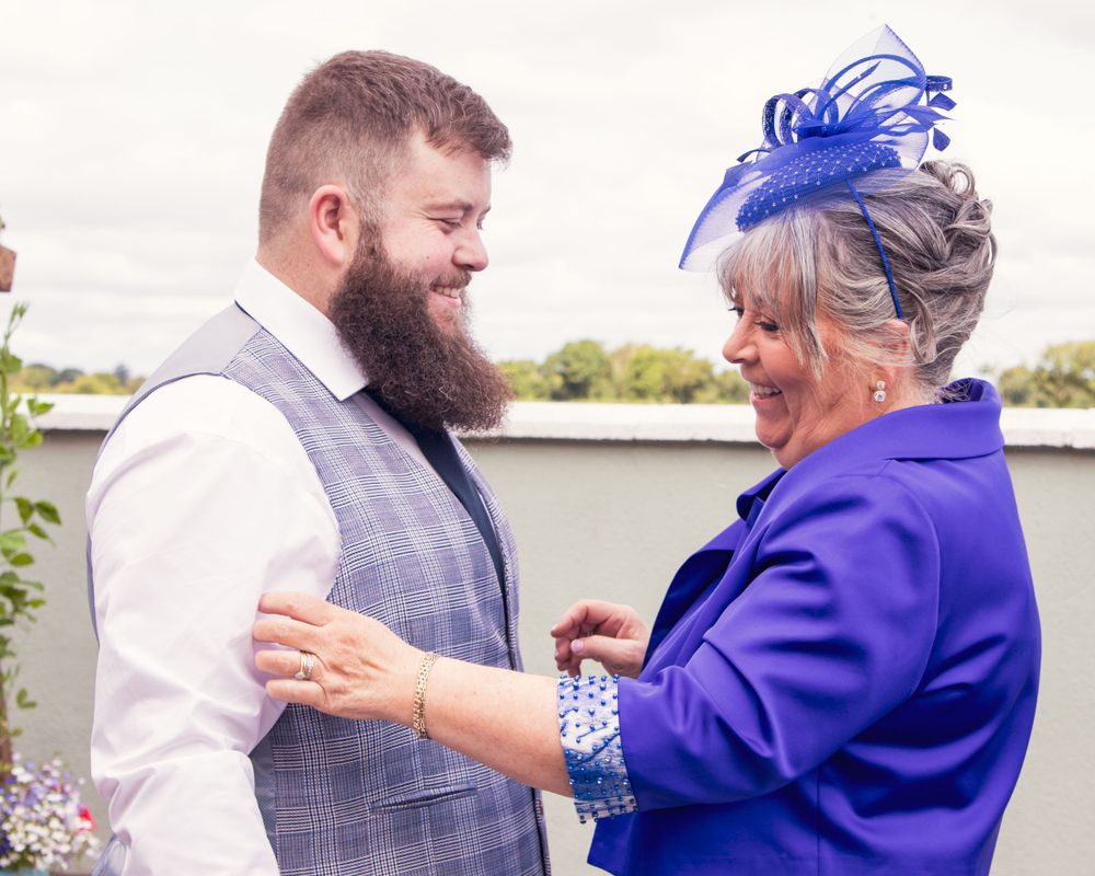 Couple in formal attire with purple accents embrace during special occasion.