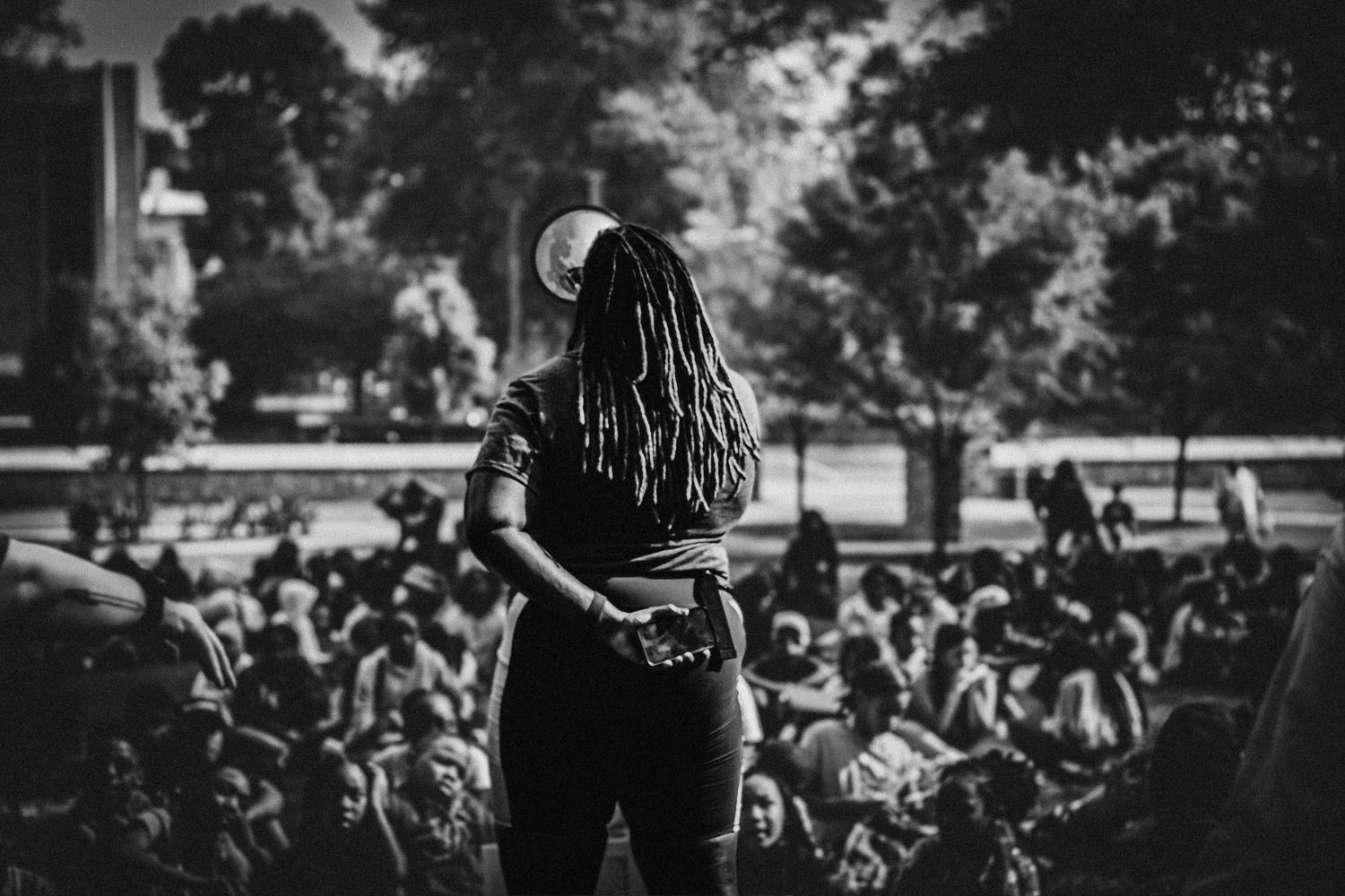 Silhouette of a performer with dreadlocks facing a large crowd at an outdoor concert.