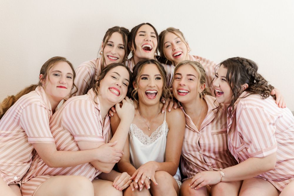 Group wearing matching pink striped robes pose together during wedding preparations.