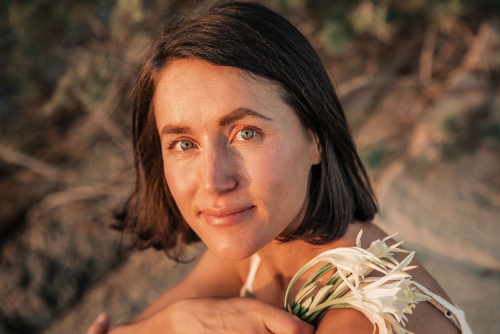 natural cosmetics branding portrait photography sunset Mallorca with flower on rocks.