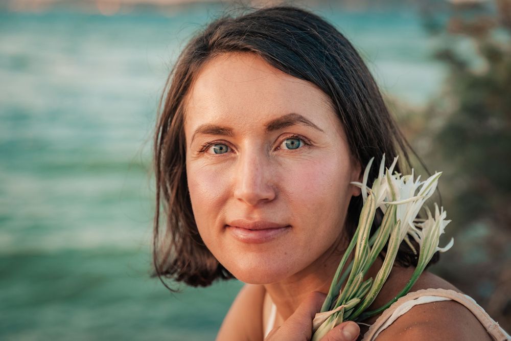 natural cosmetics branding portrait session sunset Mallorca with flower at sea.