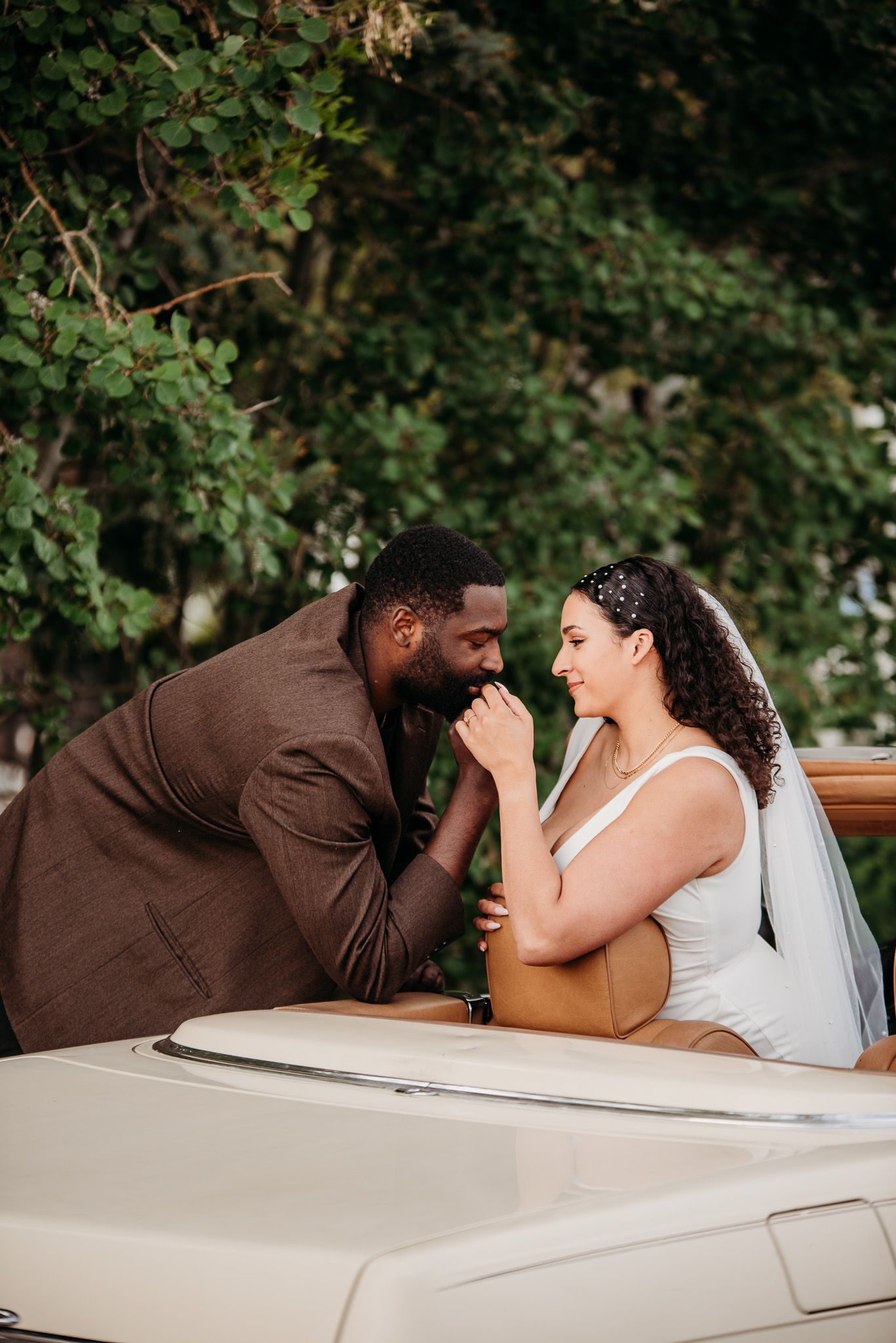 Happy couple sharing laughter while sitting in classic convertible car.