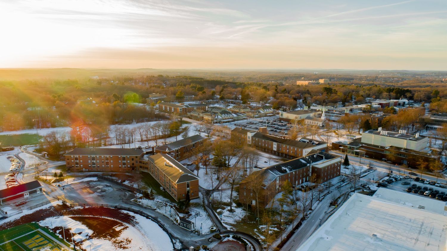 Aerial panoramic view of a snow-covered suburban landscape at sunset.