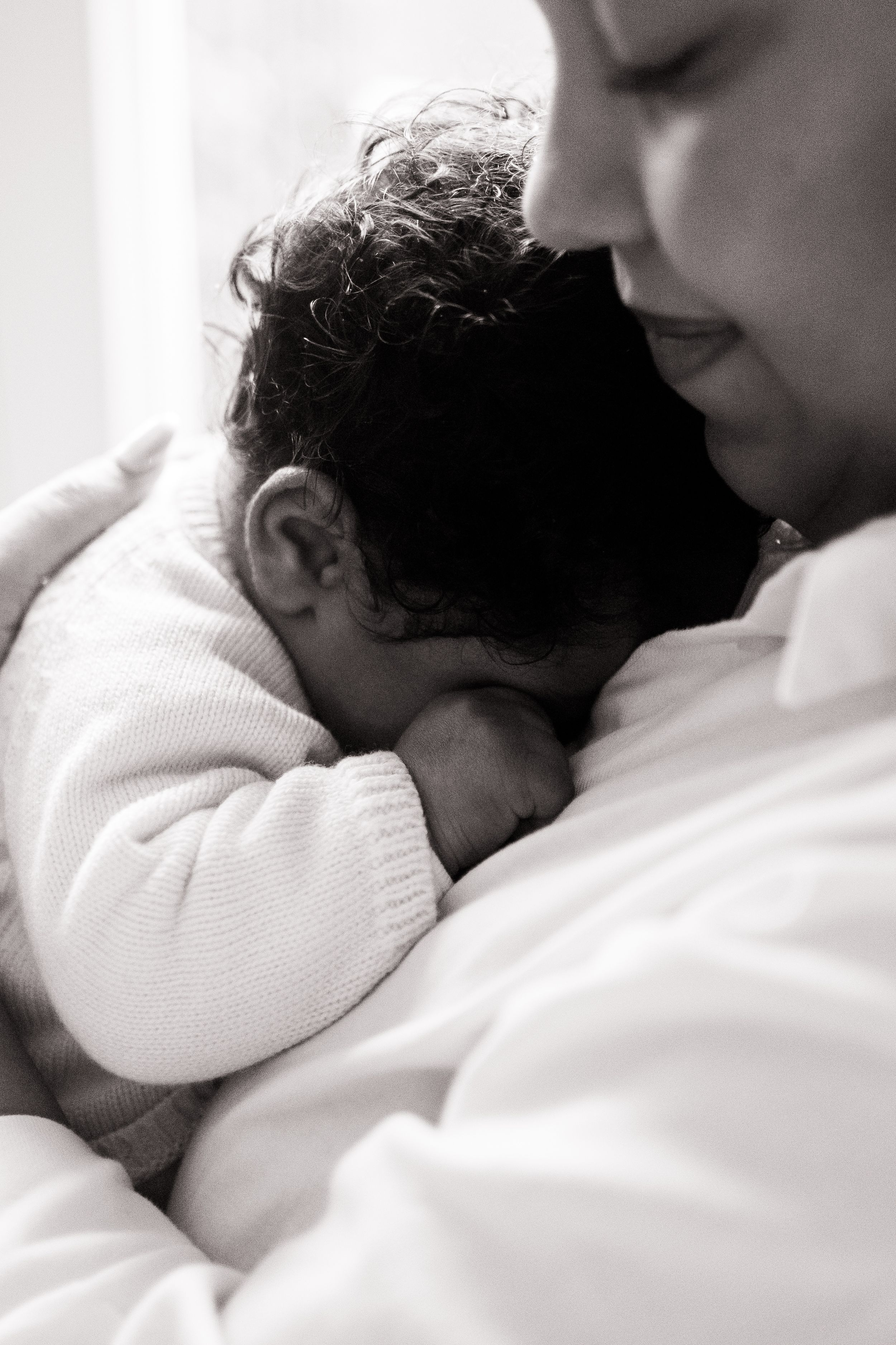 A series of intimate black and white photos showing a sleeping baby nestled against soft white fabric.