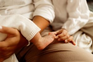 A series of tender close-up shots showing baby feet being gently held by adult hands against a white background.