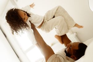 A joyful playtime moment captured against a bright white background shows gentle interaction and laughter.