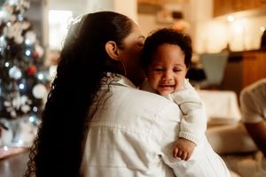 A heartwarming moment between parent and child sharing laughter with a Christmas tree in the background.