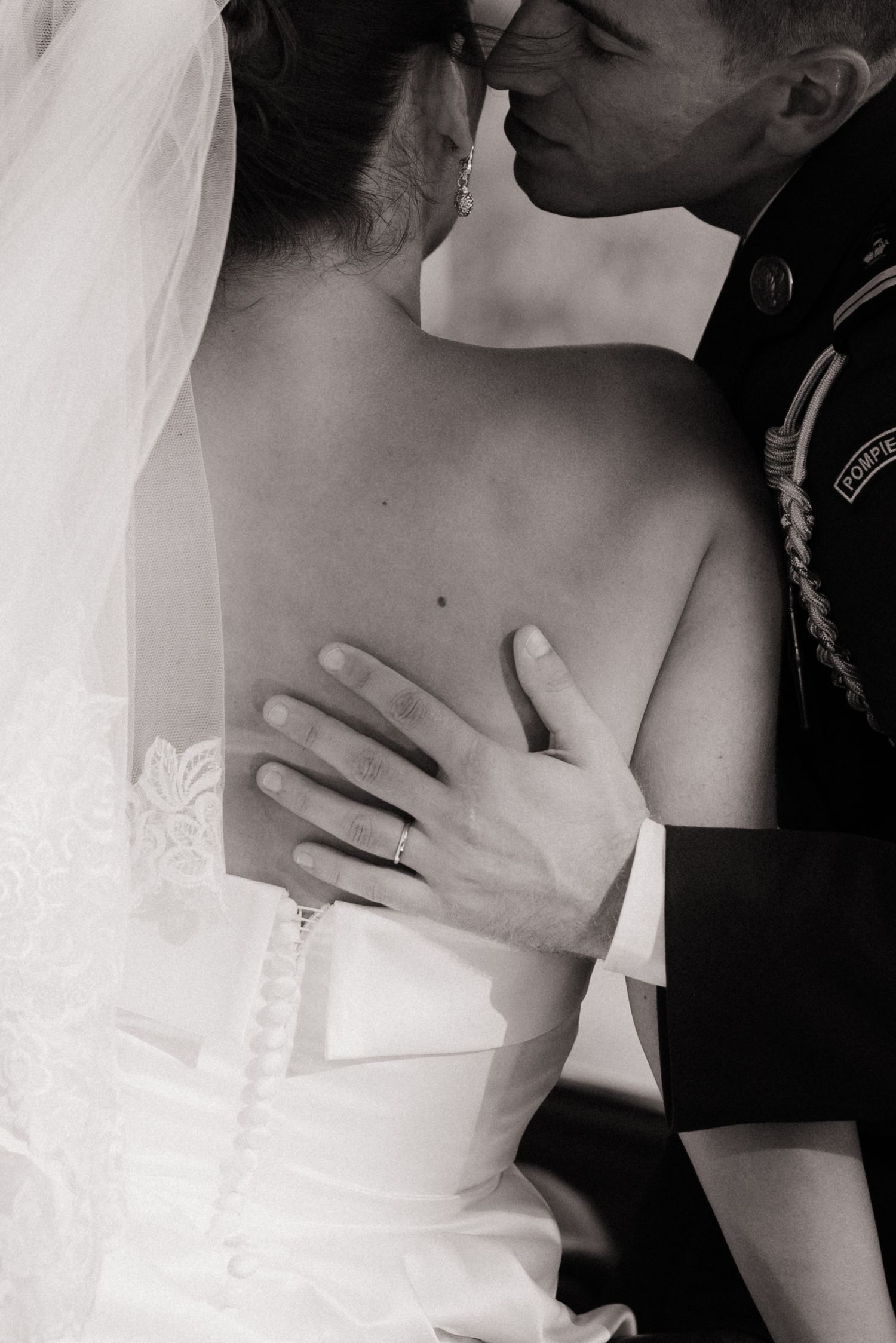Un moment romantique en noir et blanc illustrant de tendres moments entre un couple le jour de leur mariage. Le mari chuchote à l'oreille.