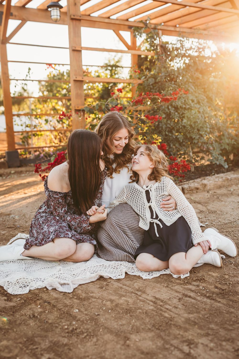Friends relax together on the ground during golden hour sunset with warm lighting and casual outdoor atmosphere.