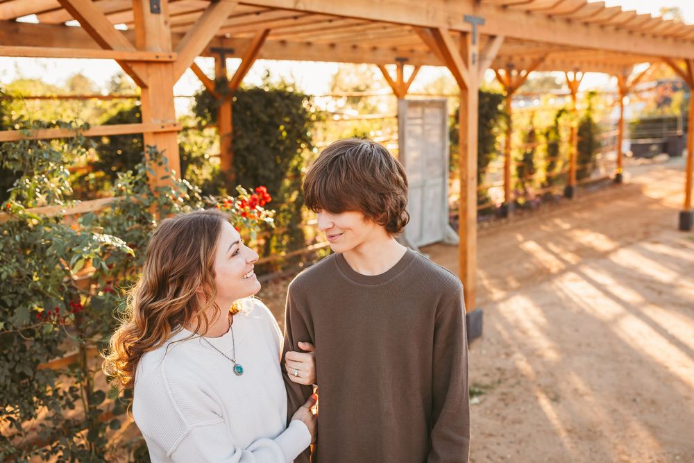 A mother and son walking and embracing under a wooden pergola during golden hour sunset lighting in Beaumont, CA.
