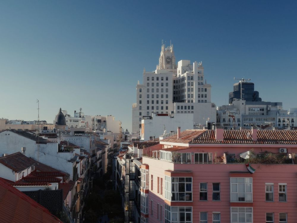 A panoramic cityscape view of urban buildings and rooftops against a blue sky in New York City.