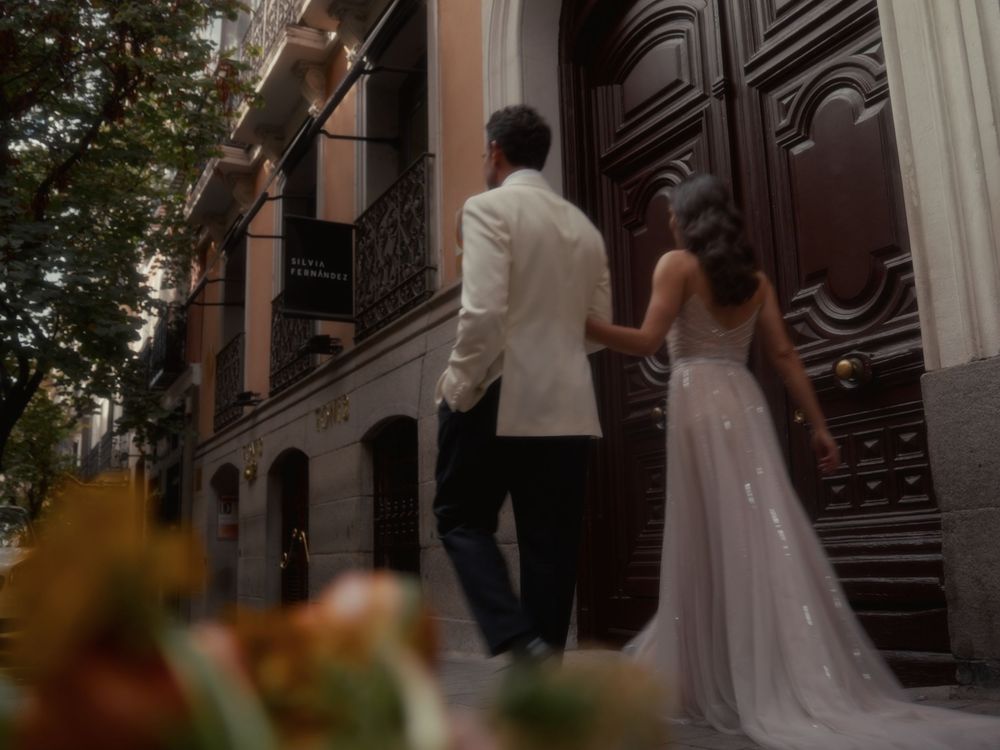 A bride and groom walk up historic brownstone steps while guests look on during an urban wedding ceremony.