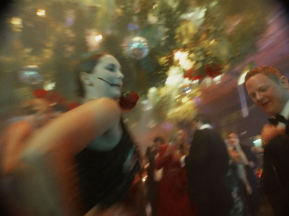 A blurry motion shot of people dancing at a festive party with decorative lights in the background.