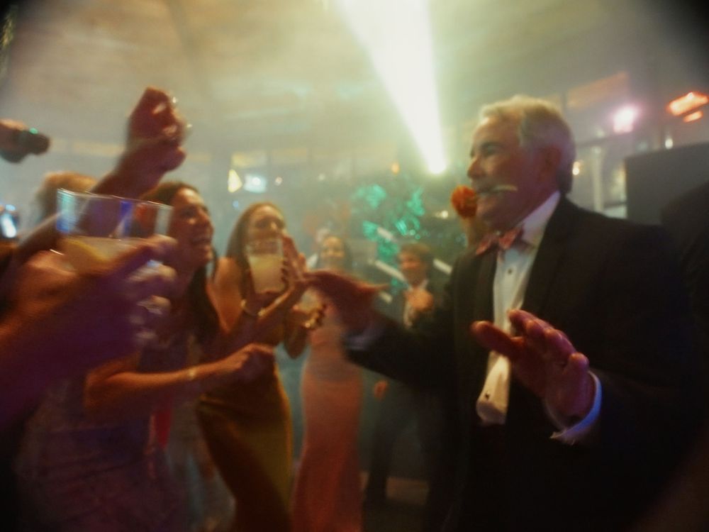 A crowd of people dancing and partying in a dark nightclub with colorful lighting effects.