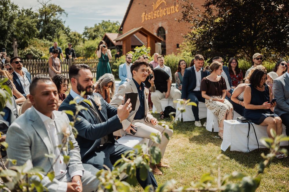 Wedding guests socializing outside a rustic brick building during an outdoor reception.