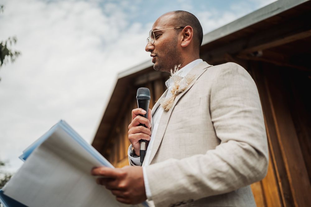 Wedding guests enjoy speeches and toasts during an outdoor reception celebration.
