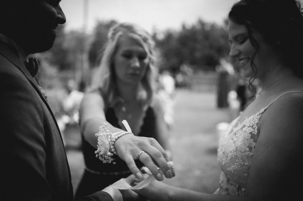 A couple exchanges rings during an intimate outdoor wedding ceremony in a garden setting.