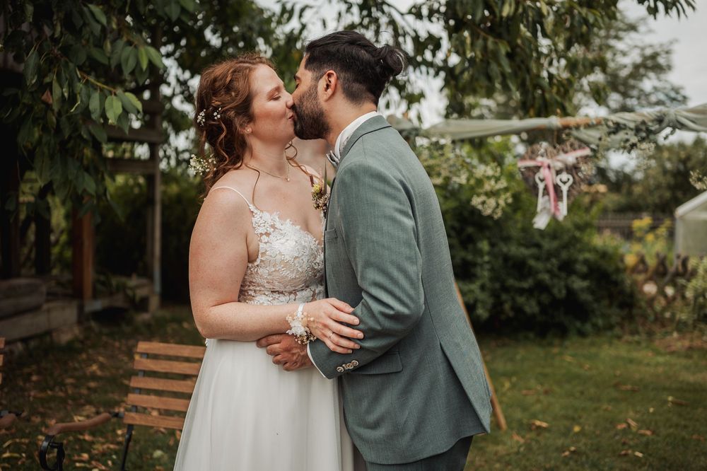 Intimate wedding couple moment in a garden setting with natural greenery and wooden benches.