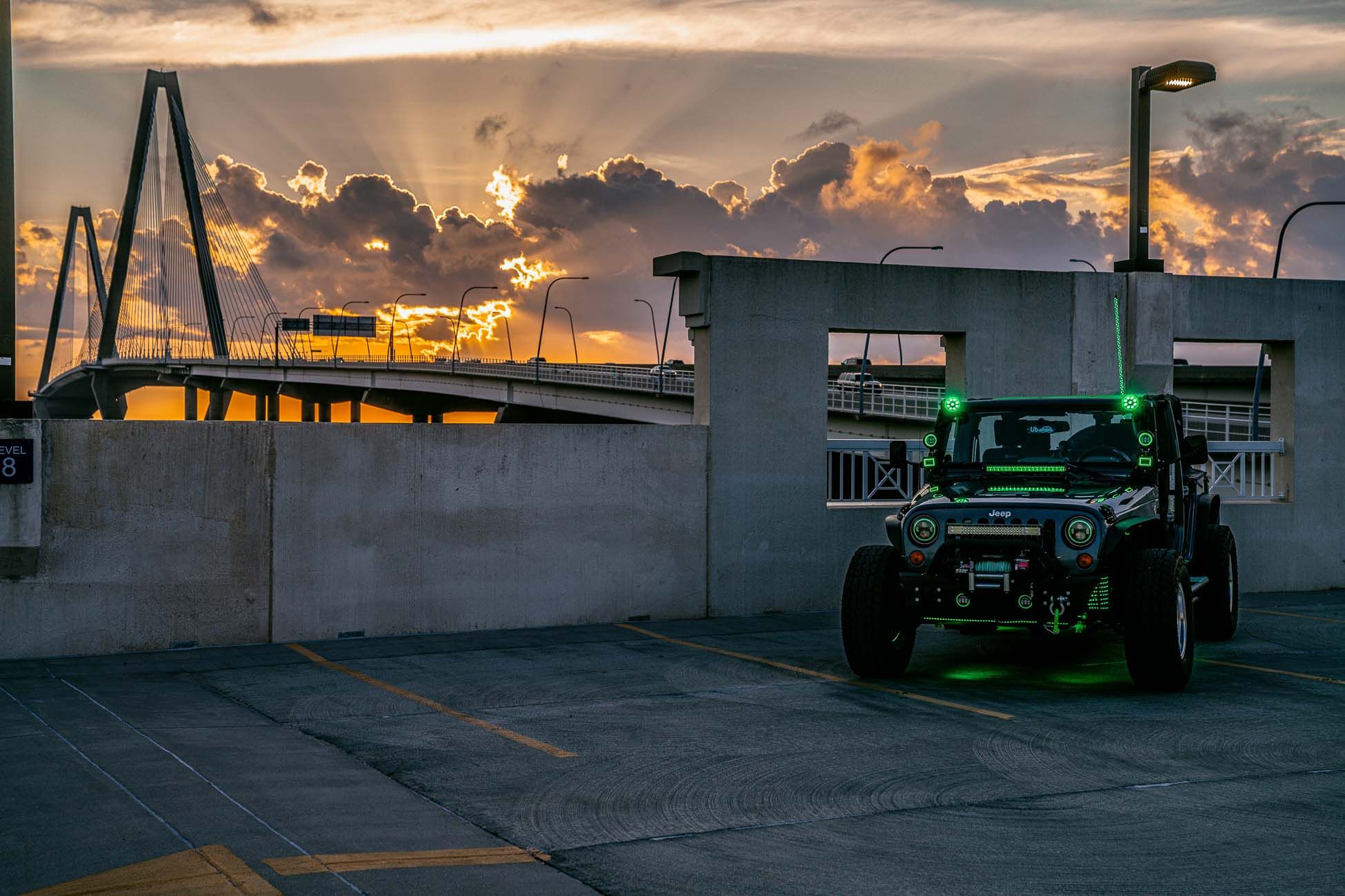 A Jeep Wrangler sits on top of a parking garage overlooking the Ravenal Bridge in Charleston, SC