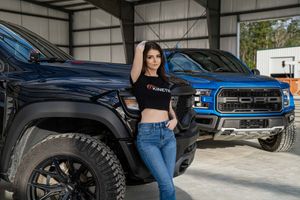 Model poses on a Dodge Ram TRX with a Blue Ford Raptor in the background for a portrait shoot in Charleston, SC
