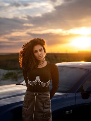 Fashion portraits at sunset with a car silhouette against a dramatic golden sky at Folly Beach, SC