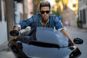 Model posing on a  sleek Harley Davidson Roadglide on a city street in Charleston, SC wearing dark sunglasses.