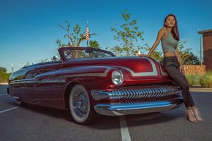 Classic red vintage Mercury car with chrome trim and model posing at sunset against natural landscape in Charleston, SC.