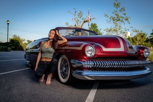 Model posing in front of a Classic red Mercury automobile parked at sunset against a blue sky in Charleston, SC.