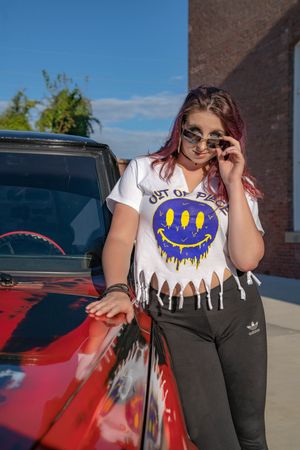 Model posing next to a red truck while wearing casual attire and sunglasses in Charleston, SC