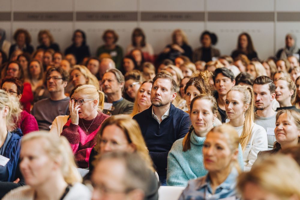 Large crowd of attendees seated in rows during a professional conference or seminar.