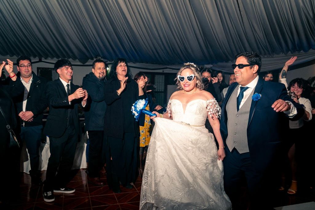 Invitados bailando y celebrando bajo carpa blanca durante la recepción de matrimonio.