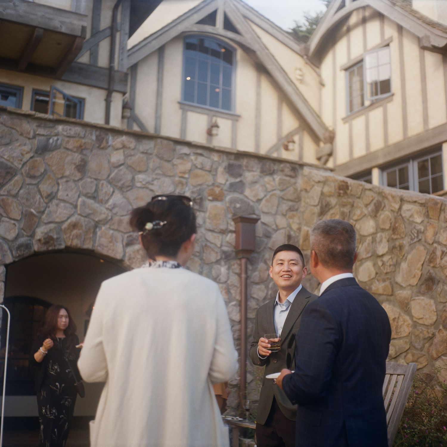 Stone building exterior with guests gathering on a paved patio area.
