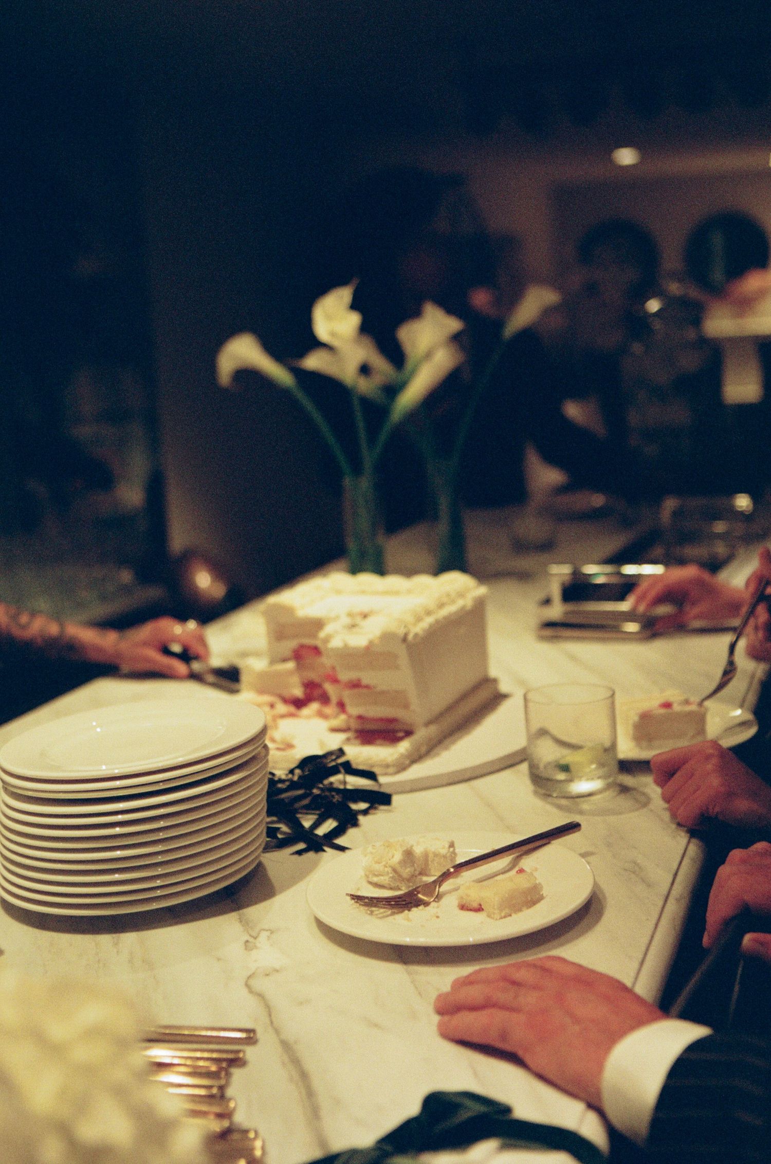 Wedding reception table with stacked white plates and cake being served.