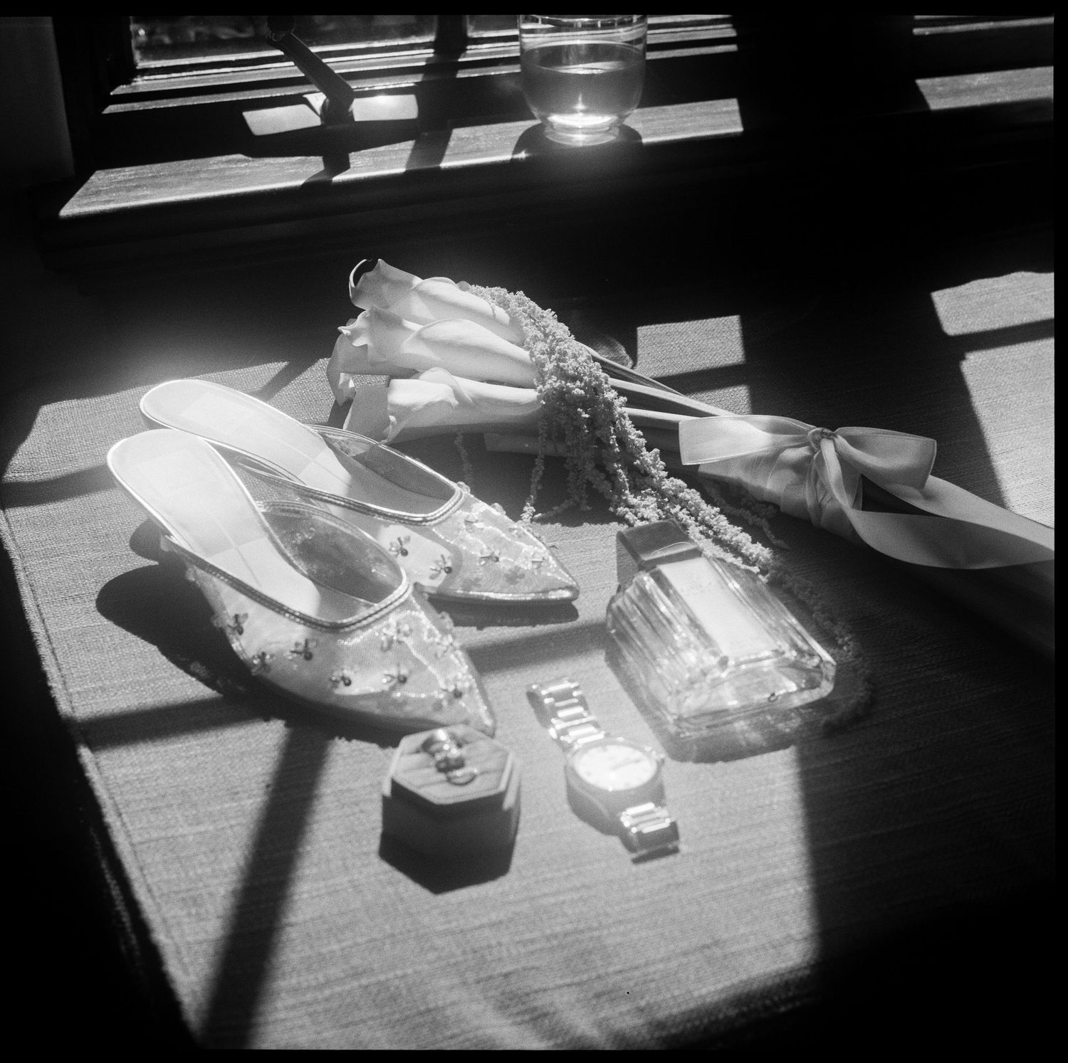 Black and white image of shoes and personal items arranged on a table in dramatic lighting.