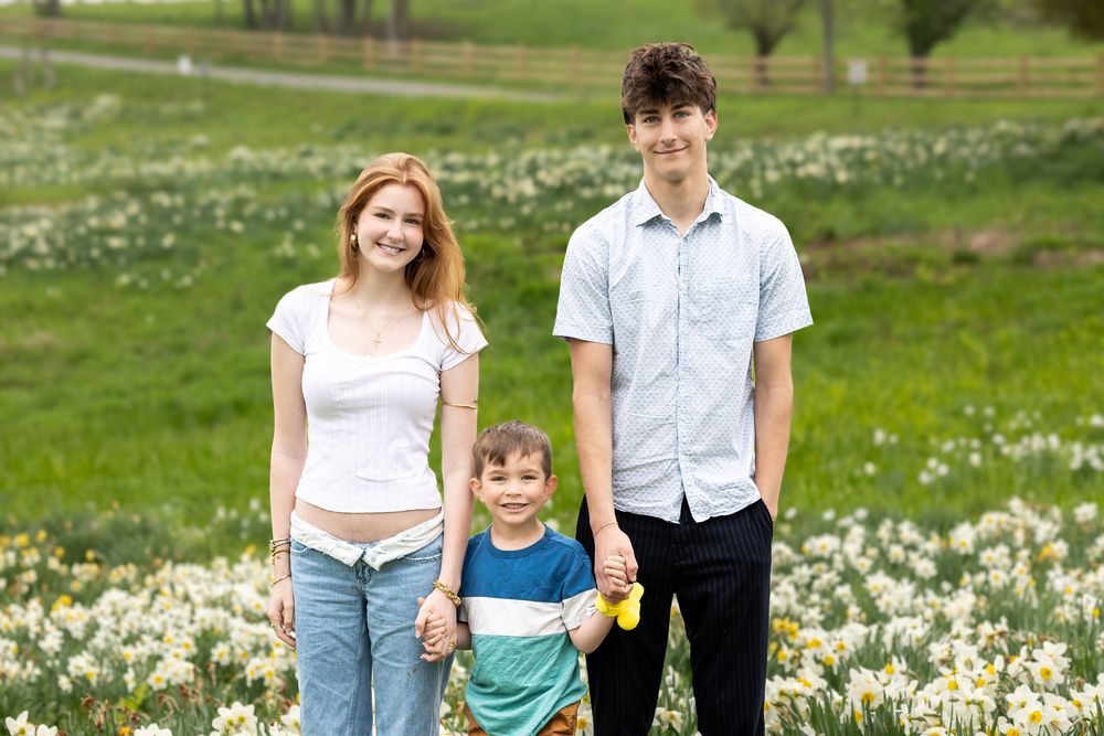 Family enjoying a spring day together in a field of blooming white wildflowers.