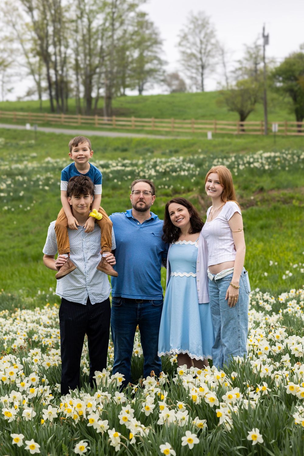 A group stands together in a blooming spring daffodil field on a green hillside.