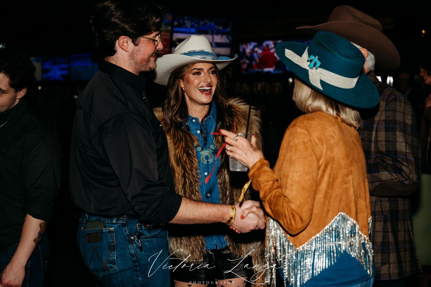 People dancing together at a western-themed country dance event with cowboy hats and boots.