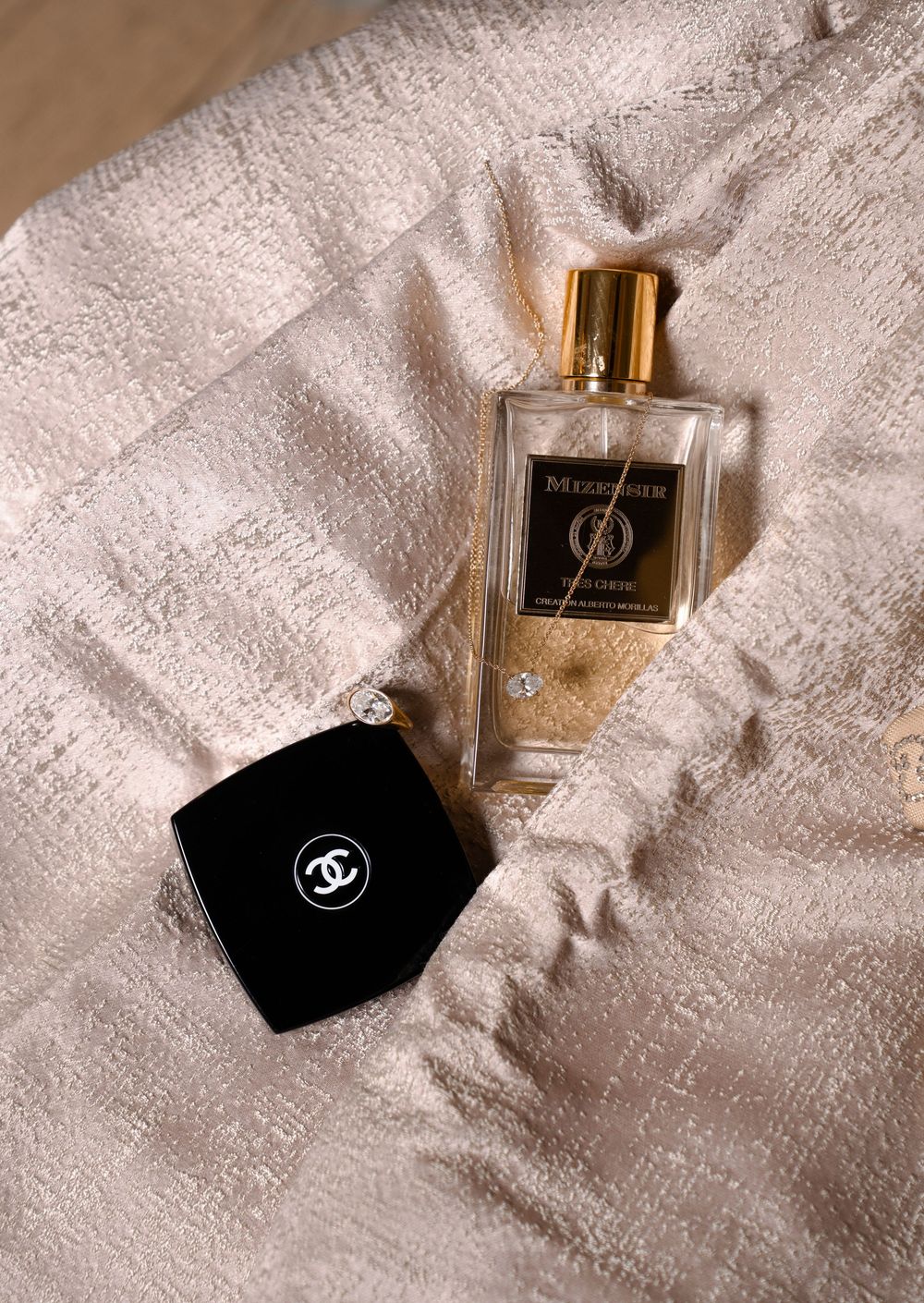 A collection of luxury perfume bottles with gold accents arranged on white textured fabric.