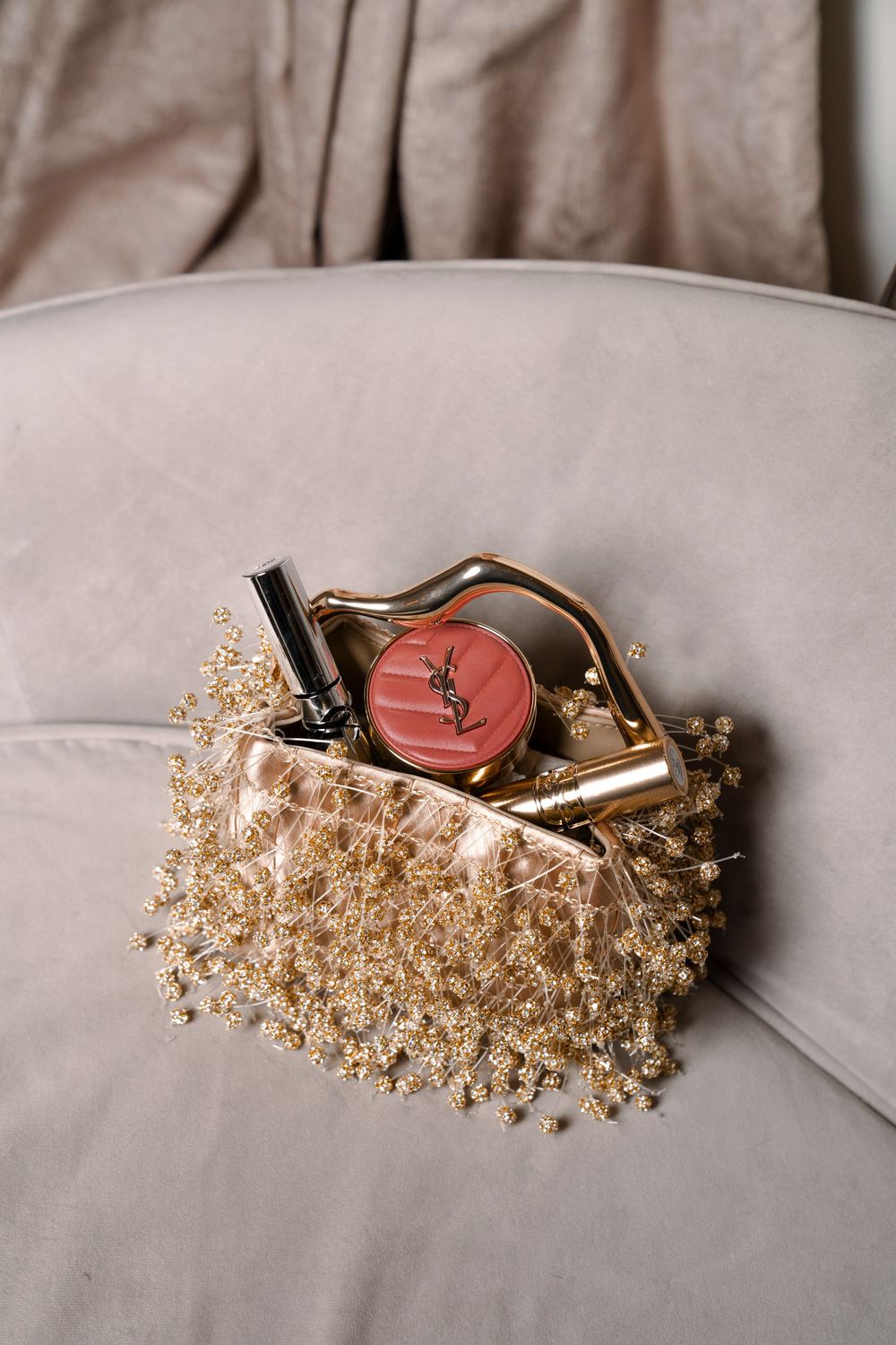 Cosmetic products arranged with delicate dried baby's breath flowers on a light gray fabric surface.