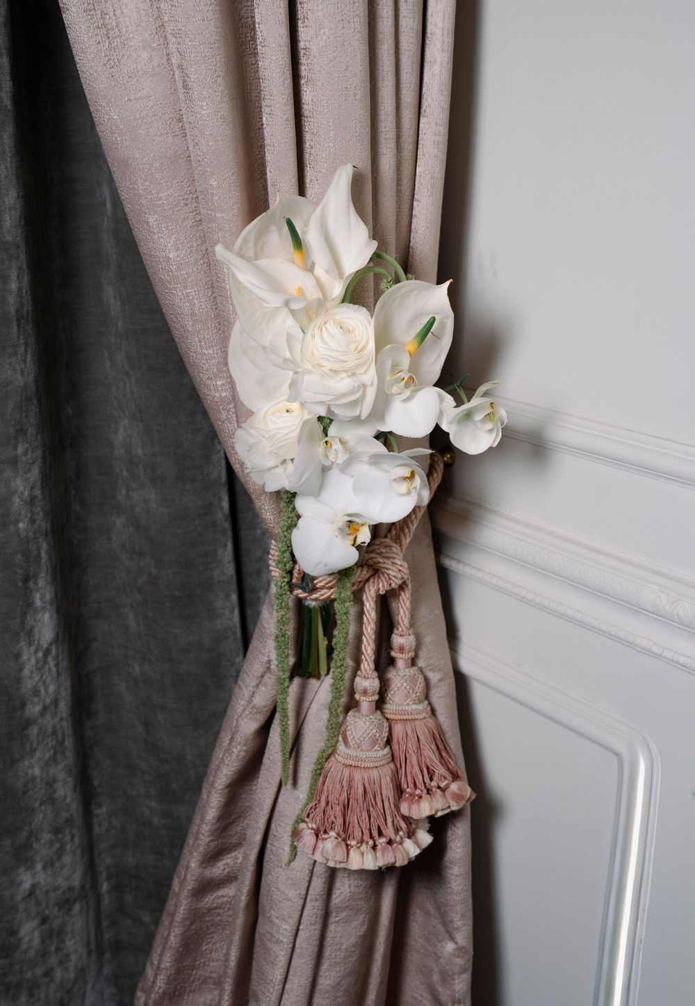 Elegant curtain tieback featuring white orchids and decorative tassels in a soft mauve color scheme.