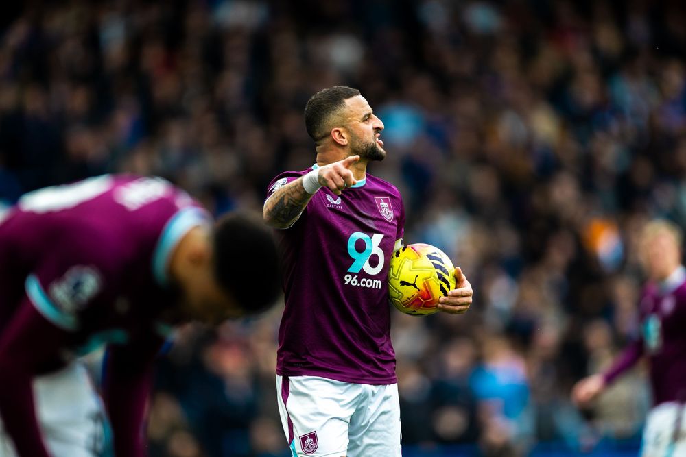 A football player in a maroon jersey celebrates after scoring during a Premier League match.
