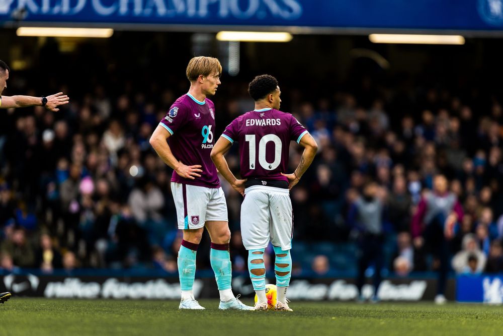 Premier League players take a knee before kickoff to support anti-racism campaign at a football stadium.