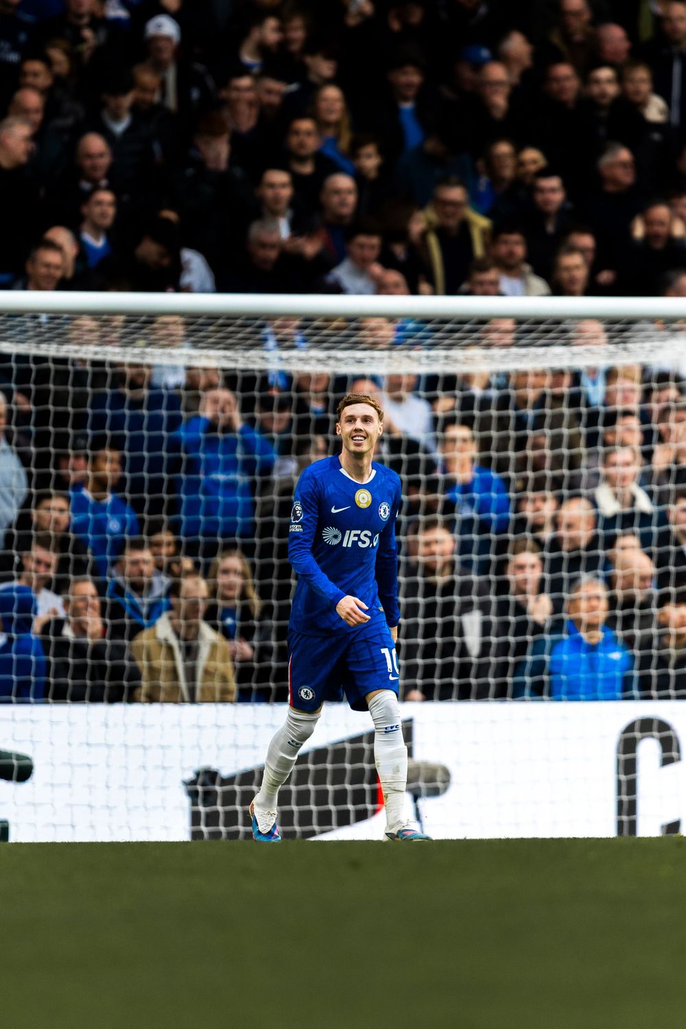 A soccer player in a blue jersey celebrates after scoring a goal during a match at a crowded stadium.