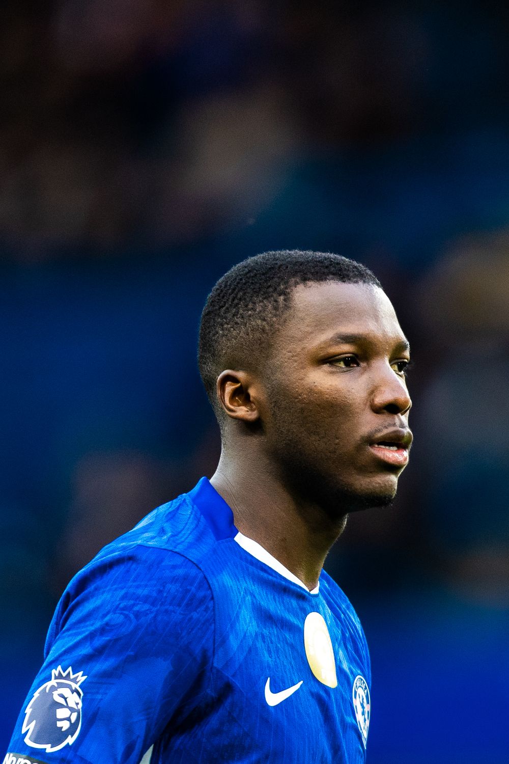 A soccer player wearing a blue Chelsea FC jersey with Premier League patch during a match.