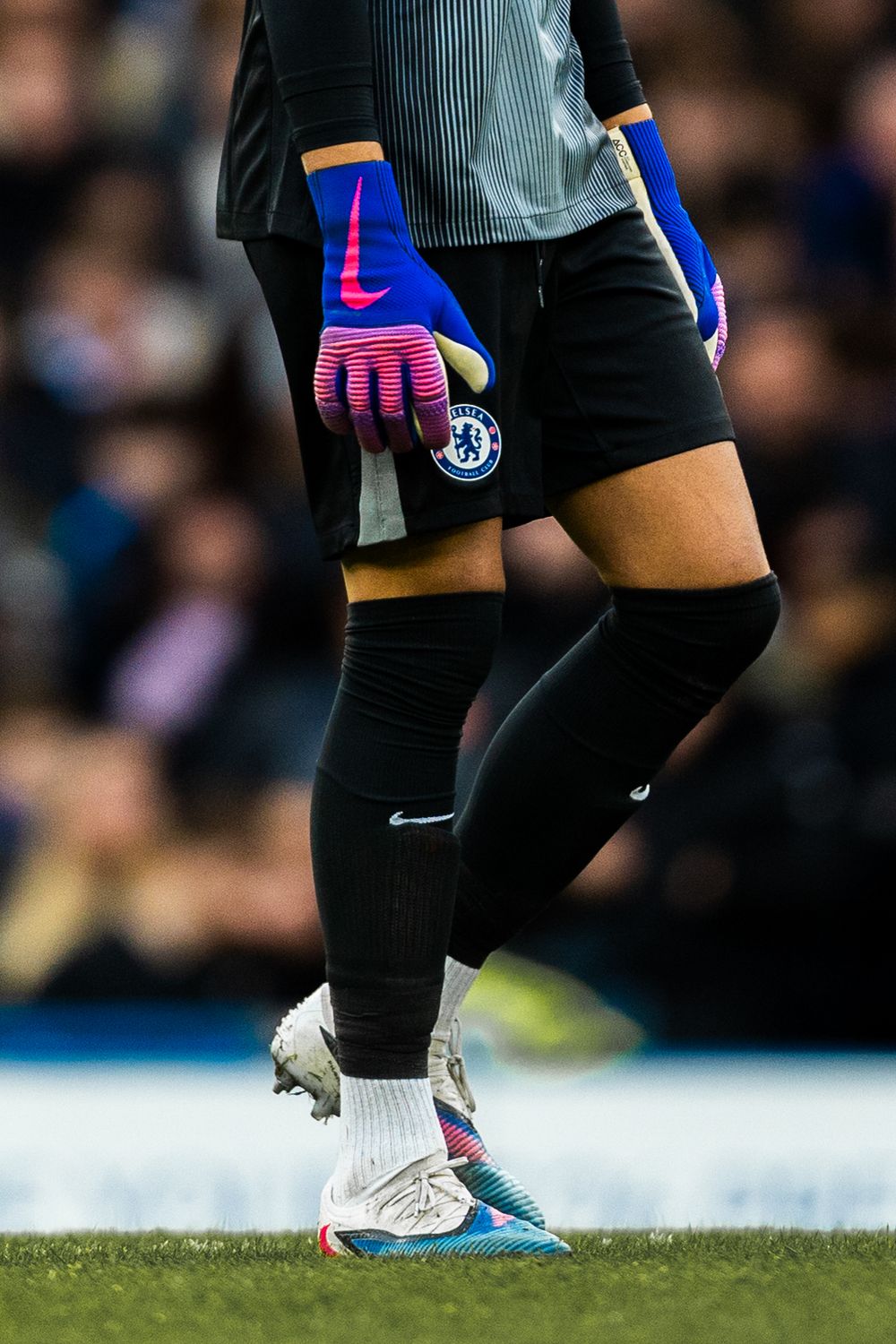 Close-up shot of a Chelsea goalkeeper's gloves and boots during a Premier League match at Stamford Bridge.