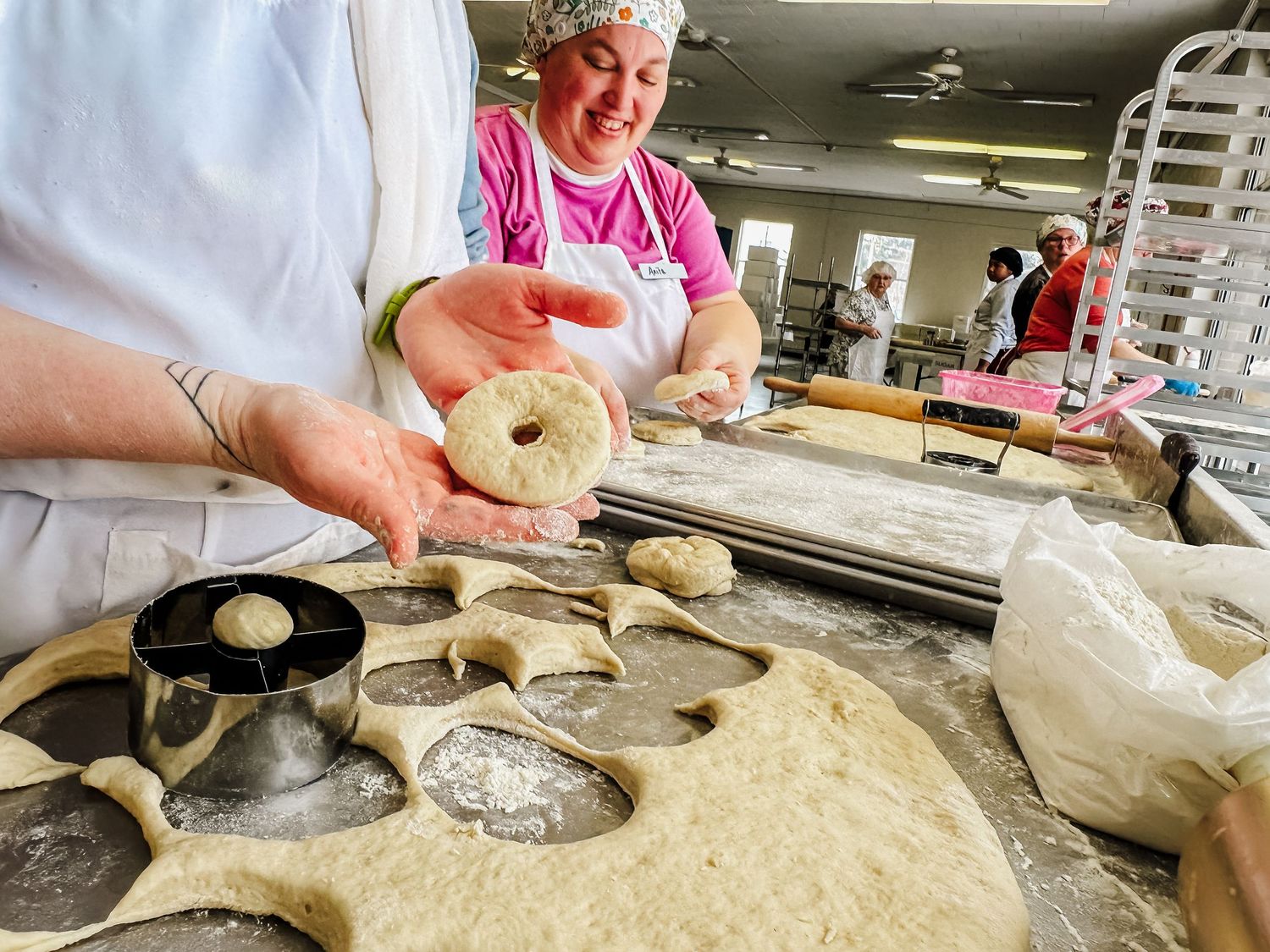 Volunteers making homemade donuts in a cozy kitchen setting for a community fundraiser.