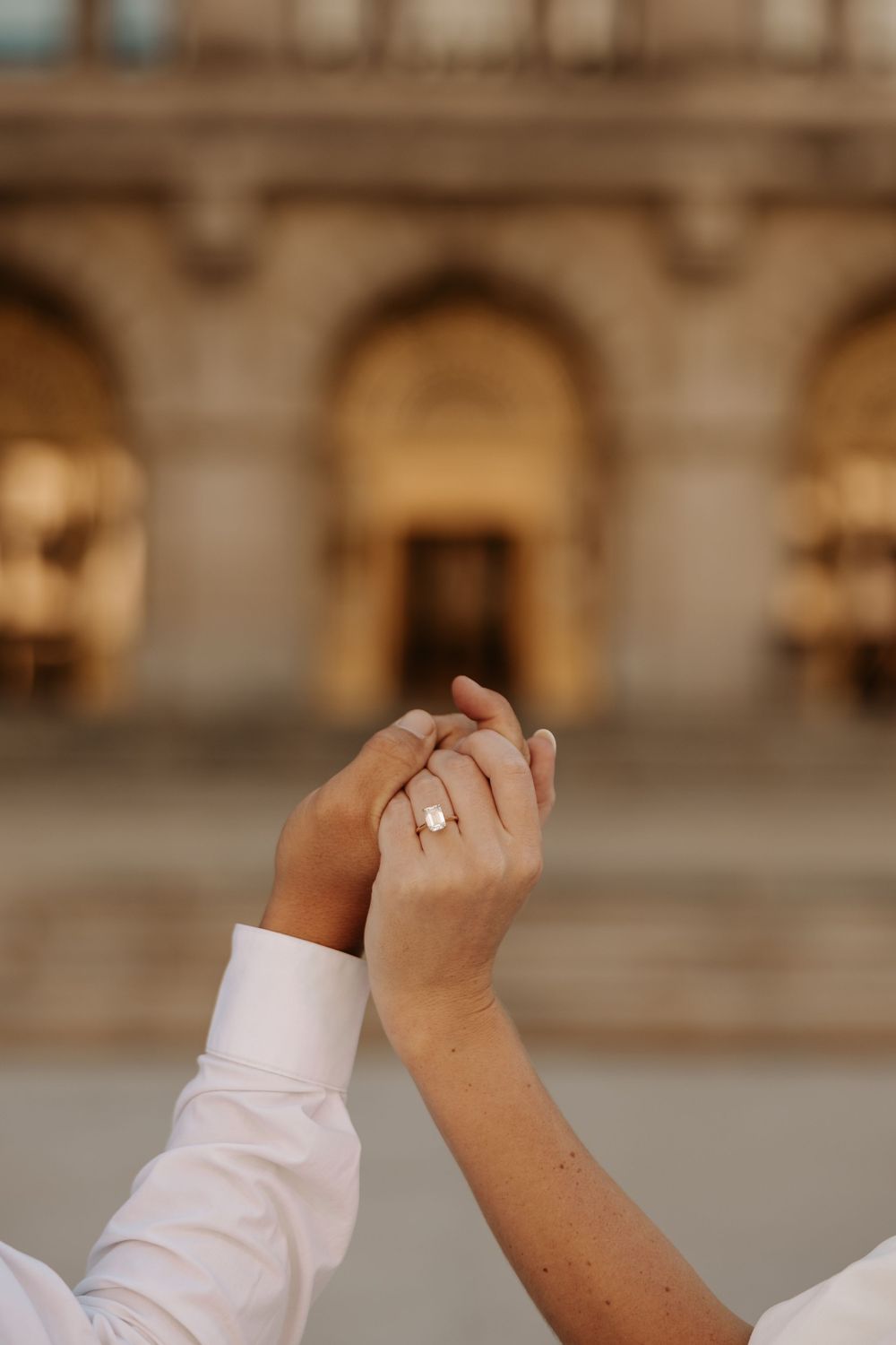Close-up sequence of hands making a fist gesture against a blurred architectural background.